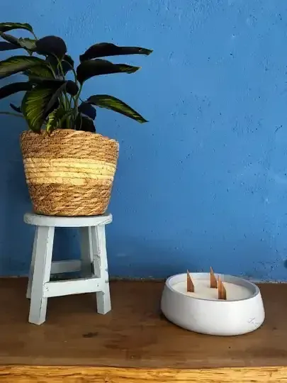 Bougie en résine minérale blanche et plante en panier sur tabouret